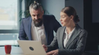 Modern bir ofis masasında iş birliği yapan profesyonel meslektaşlar dizüstü bilgisayardaki fikirleri tartışıyorlar. İş ortamında takım çalışması, iş stratejisi ve kurumsal işbirliği kavramı.
