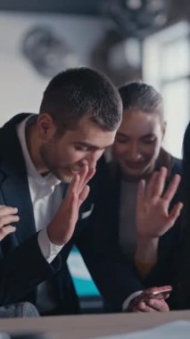 Dikey Ekran: Resmi giyinmiş mutlu profesyonellerden oluşan bir grup, modern ofisteki bir akıllı telefonun etrafında toplanırken ortalıktan kaybolan bir meslektaşıyla keyifli bir video görüşmesi yapıyor. İşbirliği kavramı
