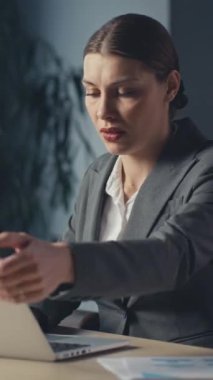 Dikey Ekran: Stresli iş kadını dizüstü bilgisayarını kapatıyor, modern ofis ortamında çalışmayı yansıtıyor. İş yeri kaygısı, karar yorgunluğu ve kurumsal tükenmişlik kavramı.