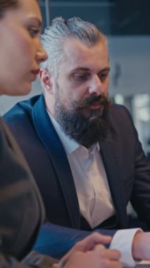 Dikey Ekran: Bir iş toplantısı sırasında modern bir ofiste fikirleri tartışan bir grup profesyonel. Şirket ortamında takım çalışması, işbirliği ve profesyonel iletişim kavramı.