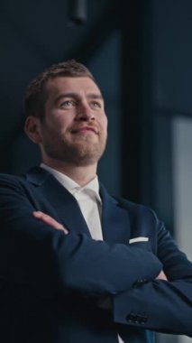 Dikey Ekran: Modern ofis ortamında kollarını kavuşturup gülümseyerek mesafeye bakan kendinden emin bir işadamı. Liderlik kavramı, hırs ve kurumsal başarı..
