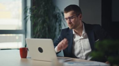 Modern bir ofiste odaklanmış bir iş adamı, bir dizüstü bilgisayar üzerinde çalışıyor, düşünceli ve analitik görünüyor. Konsantrasyon, profesyonel odaklanma ve iş analizi kavramı.