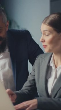 Dikey Ekran: Modern bir ofis masasında iş birliği yapan profesyonel meslektaşlar, dizüstü bilgisayardaki fikirleri tartışıyorlar. İş ortamında takım çalışması, iş stratejisi ve kurumsal işbirliği kavramı.