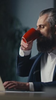 Dikey Ekran: Modern bir ofiste dizüstü bilgisayar üzerinde çalışırken iş adamı bir telefonla araya girdi. Çoklu görev, iş iletişimi ve profesyonel iş akışı kavramı.