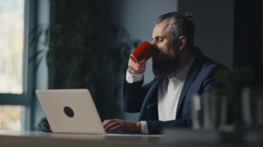 Modern bir ofiste dizüstü bilgisayarla çalışırken iş adamı bir telefonla araya girdi. Çoklu görev, iş iletişimi ve profesyonel iş akışı kavramı.