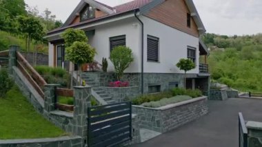 Taş cepheli, bahçeli, yemyeşil yemyeşil, sakin bir çevrede yer alan modern bir aile evi. Çağdaş banliyö yaşamı ve ev sahipliği kavramı.