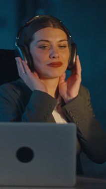 Dikey Ekran: Takım elbiseli genç bir kadın loş bir ofiste geç saatlere kadar çalışırken müzik dinlemekten hoşlanıyor. Birlikte şarkı söylüyor, kulaklık takıyor, rahatlama ve odaklanma gösteriyor..