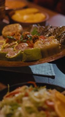 Dikey: Geleneksel doldurulmuş sebzeler, kabak, dolma biber, üzüm yaprakları da dahil olmak üzere, rahat bir yemek ortamında kırsal bir ahşap tabakta servis ediliyor. Özgün ev yapımı Balkan ve Türk mutfağı.