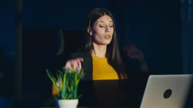 Genç iş kadını ya da müteahhit gece geç saatlere kadar loş bir ofiste çalışırken yorgunluk belirtileri göstererek esniyor. Aşırı çalışma, yorgunluk ve uzun çalışma saatleri kavramı..