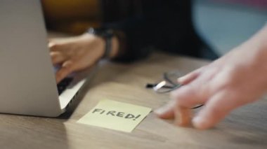 Ofiste dizüstü bilgisayarda çalışan profesyonel bir kadın işten çıkarma notu alır. Şok olmuş ve endişeli tepkisi beklenmedik iş kaybının duygularını yansıtıyor. İşten çıkarılma kavramı.