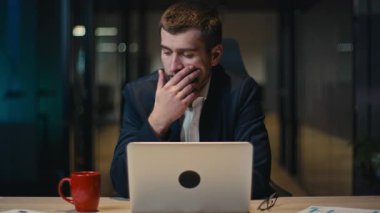 Endişeli işadamı, loş bir ofiste geç saatlere kadar çalışıyor ve bilgisayarına odaklanmış durumda. İş stresi, sorun çözme, iş sorunları, karar verme ve baskı kavramı.