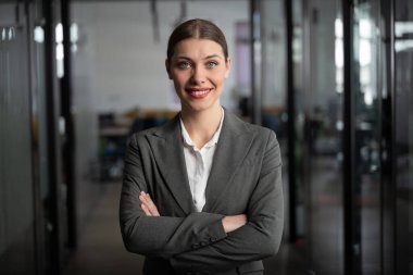 Modern bir ofiste kendine güveni tam bir iş kadını, kolları bağlı, resmi bir takım elbise giyiyor. Liderlik, güven. Yönetici, yönetici, girişimci, danışman, CEO, yönetmen, yönetici.