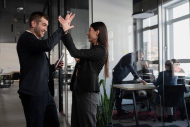 İş adamları modern bir ofiste başarıyı beşlikle kutluyorlar. Profesyonel bir ortamda takım çalışması, başarı, işbirliği ve kurumsal kültür kavramı.