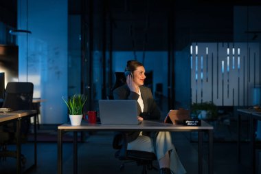 Modern bir ofiste genç bir bayan girişimci, işe ara verirken kulaklıkla müzik dinliyor. Rahatlama, odaklanma, iş-yaşam dengesi, teknoloji endüstrisinde verimlilik kavramı.