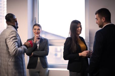 Modern bir ofiste kahve molası sırasında iş dünyasından profesyoneller iletişim kuruyor. İş ortamında kurumsal iletişim, takım çalışması ve profesyonel ilişkiler kavramı.