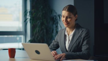 Ofiste dizüstü bilgisayarda çalışan güler yüzlü asker ya da koordinatör kendine güvenle çevrimiçi etkileşim içinde. Dijital iletişim, uzaktan çalışma, üretkenlik ve profesyonel başarı kavramı.