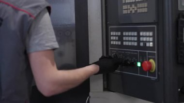 CNC makine kontrol panelini çalıştıran fabrika işçisi, mekanik işlem sırasında ayarları ayarlıyor. Otomasyon, endüstriyel kontrol, üretim ve hassas mühendislik kavramı.