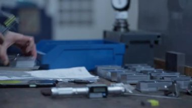 Endüstriyel bir ortamda mekanik metal bileşenlerini elle inceleyen ve ölçen bir mühendisin yakın çekimi. Hassas imalatta kalite kontrolü kavramı.