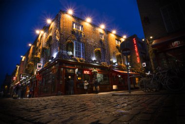 Cobblestone caddesini aydınlatan renkli ışıklarla dolu, hareketli bir gece barı.