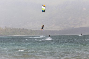 A thrilling moment of a skilled kiteboarder soaring high above sparkling waves in a beautiful coastal setting