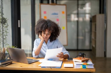 İş kadını oturuyor ve devam eden belgelere ya da işlere bakıyor. Stresli iş kadını analisti evrak işlerine bakıyor..
