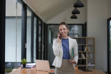 Akıllı iş kadını elinde belgelerle ofisteki masada konuşuyor..