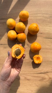 Ahşap masada elinde lezzetli, olgun kayısılar