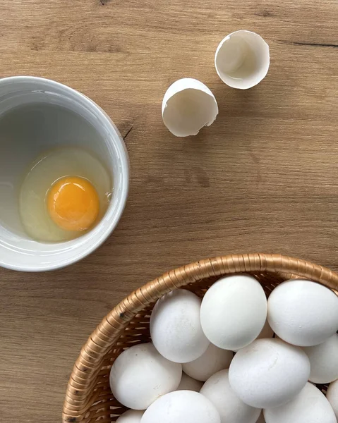 Farm eggs, white lie on a wooden table and in a basket, close-up. Organic food concept