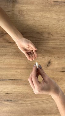 Çocuk annesinin elinden omega-3 jel kapsüllerini alıyor.