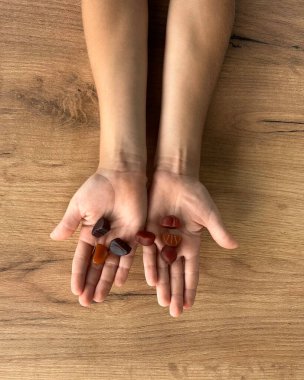 Tahta bir masanın üzerinde haplarla çocuk eli.