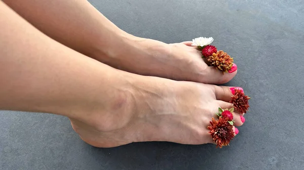 Perfect pedicure female legs in spa with flowers