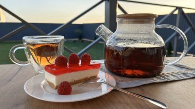 Kahvaltıda bir bardak sıcak çay servis edilir. Tahta bir masada, kekle birlikte.