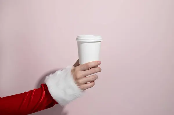 A paper cup in the hands of a woman in a Christmas costume. Christmas. New Year