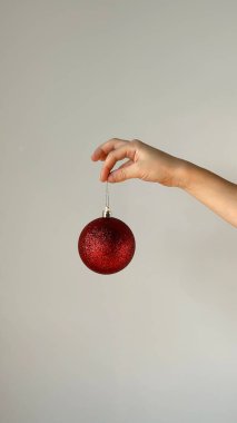 El ve kırmızı top ile Noel konsepti - Noel ağacı oyuncağı. Gri arkaplanda izole.