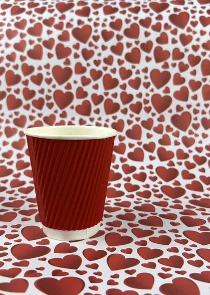 red paper cup on a background of red hearts. Valentine's day concept