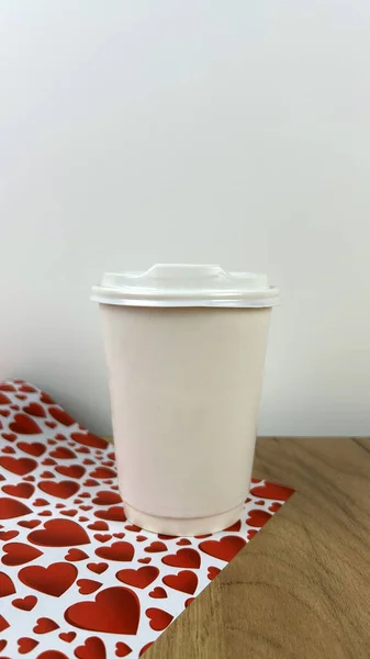 a white paper cup on a background of red hearts. Valentine\'s day concept