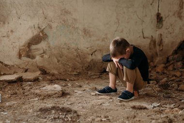 Üzgün, küçük bir Ukraynalı çocuk, bir anaokulu öğrencisi, yıkılmış evinin yıkıntılarında oturuyor. Koyu renk giysiler içinde bir roketin gelişi ve ağlamaları üzerine.