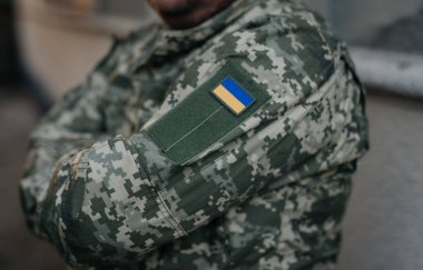 Omzunda ulusal bayrak olan askeri üniformalı Ukraynalı asker. Dramatik arka plan, soğuk renkler. Savaş ve barış kavramı, Ukrayna ve Rusya arasındaki çatışma.