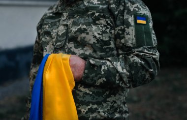 Ukraynalı bir asker ulusal bayrağı bir güç sembolü olarak tutuyor. Ukrayna 'da savaş. Kazaklar Günü ve Ukrayna 'nın savunucusu. Dramatik arkaplan.