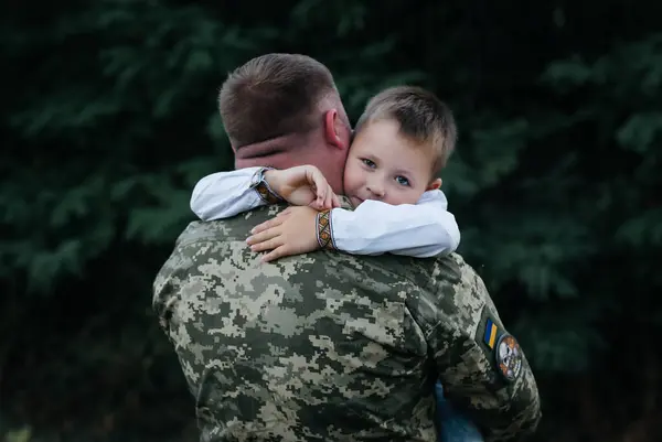 A little boy says goodbye to a soldier. The son hugs the father of the Ukrainian soldier. The Ukrainian defender said goodbye to his family. Mobilization of Ukrainian men. War in Ukraine.