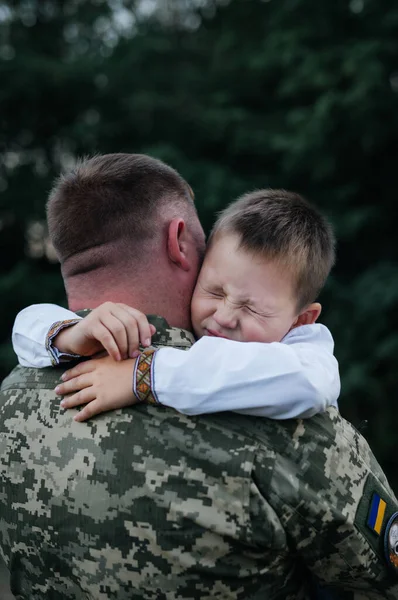 A little boy says goodbye to a soldier with his eyes closed. The son hugs the father of the Ukrainian soldier. The Ukrainian defender said goodbye to his family. War in Ukraine.