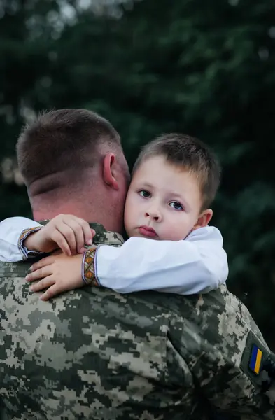 A little boy says goodbye to a soldier. The son hugs the father of the Ukrainian soldier. The Ukrainian defender said goodbye to his family. Mobilization of Ukrainian men. War in Ukraine.