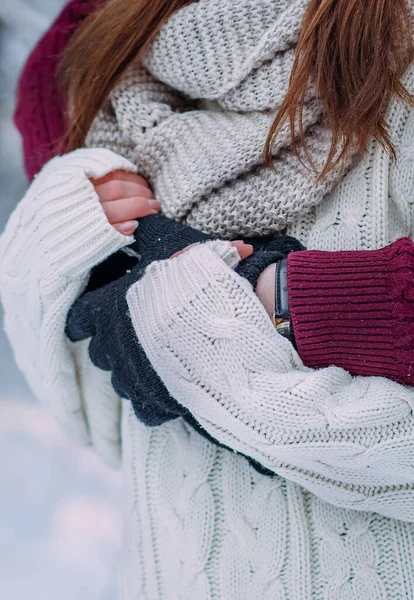 Close-up of hugging hands. A couple in white and red clothes, the man stands behind the girl and hugs her in winter. Unity concept. Soft focus.