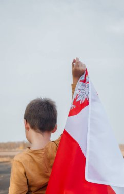 Küçük bir çocuk Polonya bayrağını elinde tutuyor. Ulusal bayrağı olan bir çocuğun portresi. Dikiz aynası. Ulusal bayramlar ve vatanseverlik olayları kavramı. Vatanseverlik. Bağımsızlık Günü.