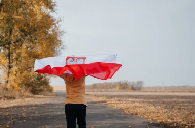 Küçük bir çocuk doğada Polonya bayrağını tutuyor. Elinde titreyen bir ulusal bayrak ile bir çocuk yol boyunca koşuyor. Ulusal bayramlar ve vatanseverlik olayları kavramı. Bağımsızlık Günü.