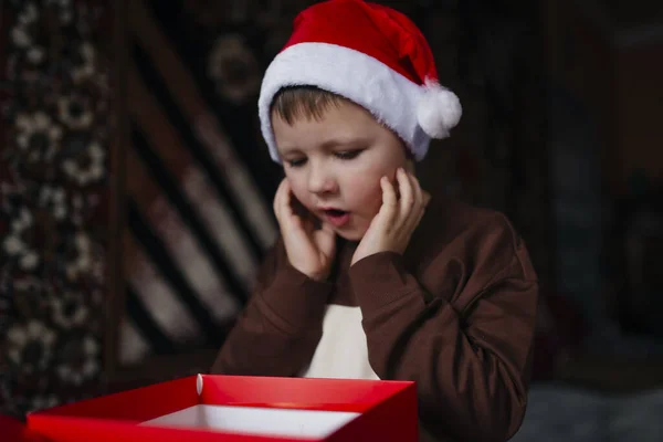 Bambino Con Cappello Rosso Natale Apre Una Scatola Regalo Ricevuta Foto Stock Royalty Free