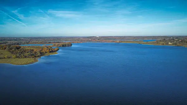 Ormanla çevrili bir gölün hava aracı görüntüsü.