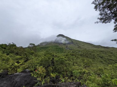 Arenal Volkanı, La Fortuna, Kosta Rika. La Fortuna, Kosta Rika 'daki zirveyi çevreleyen bulutlu Arenal Volkanı. Yeşil yapraklar ve tropikal ormanlar.