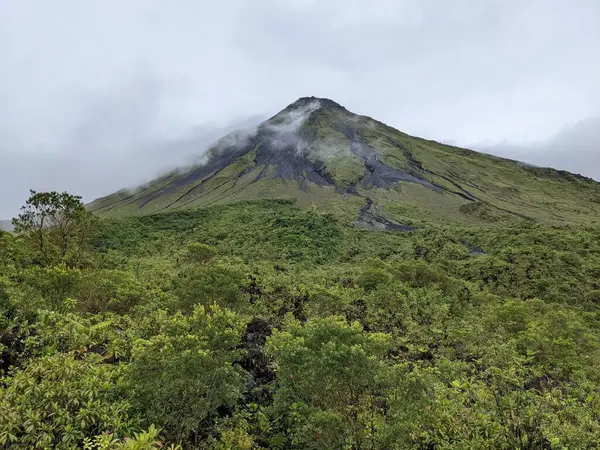 Arenal Volkanı, La Fortuna, Kosta Rika. La Fortuna, Kosta Rika 'daki zirveyi çevreleyen bulutlu Arenal Volkanı. Yeşil yapraklar ve tropikal ormanlar.
