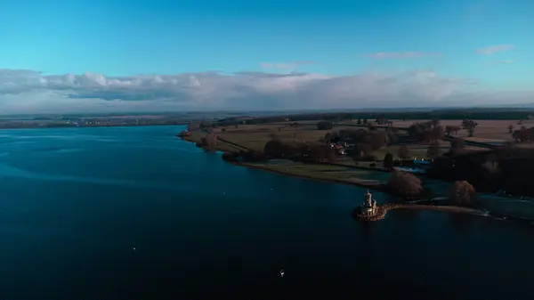İngiltere 'de Rutland Su Gölü rezervuarındaki Normanton Kilisesi Manastırı' nın aşağı tarafındaki hava manzarası gün batımında açık gökyüzü olan soğuk ve buzlu havalarda.. 